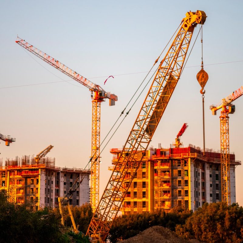 A large crane standing over a construction site at sunset.